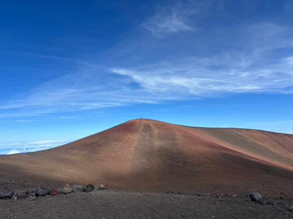 Reddish brown Mauna landscape beneath an expansive blue sky